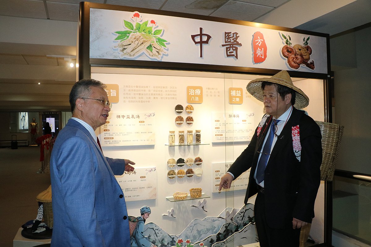 中國醫藥大學立夫中醫藥博物館「3D經絡銅人互動裝置、國醫堂及中醫方劑展」揭幕 2 裝扮採醫農民的洪明奇校長聽取林昭庚講座教授介紹中醫方劑
