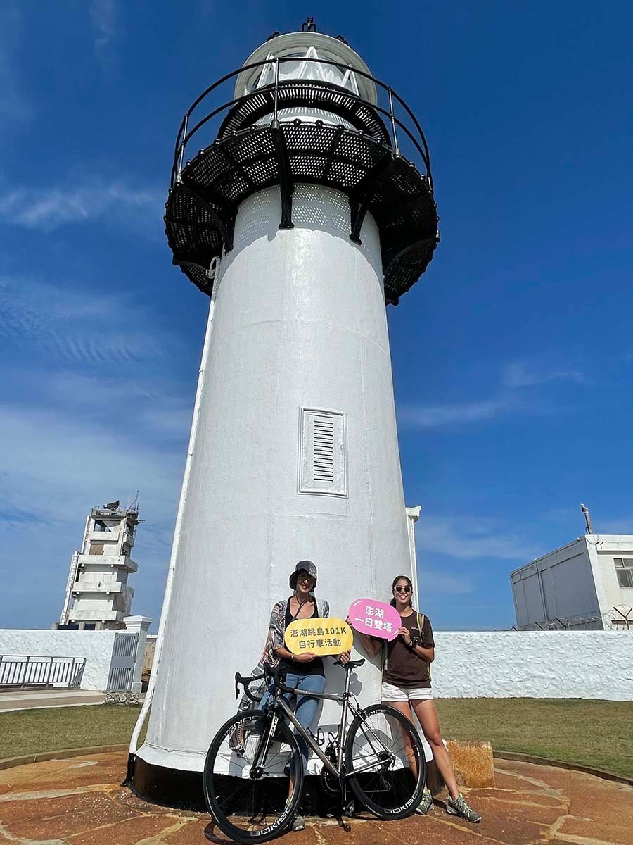 鐵人主播夏嘉璐（左）、侯以理（右）於澎湖跳島101Ｋ活動經典路線漁翁島燈塔前合影，解鎖澎湖一日雙塔