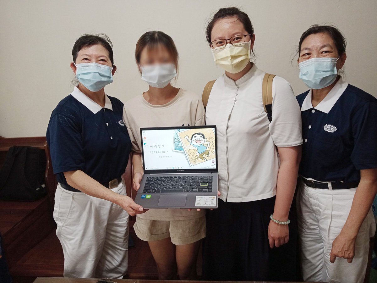 學子拿到全新筆電，高興與志工合影。