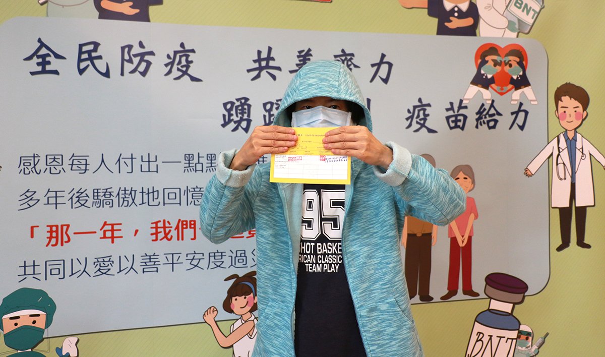臺中慈濟醫院27日開打BNT疫苗 1 林女士成功接種BNT疫苗後,開心展示黃卡。