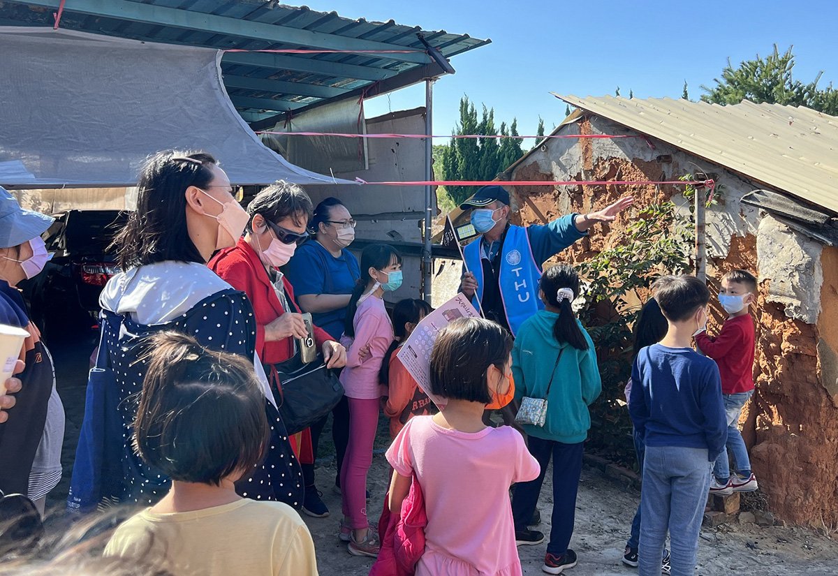 「社區走讀」解說當地紅飛沙的由來，以及說明土角厝的建築方式。