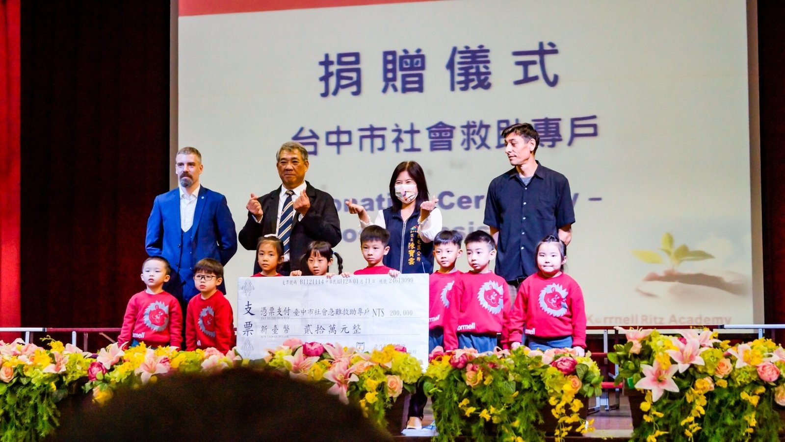 麗喆中小學捐贈儀式，校長蕭百凱（中左）與西屯區長陳寶雲（中右）與師生合影。